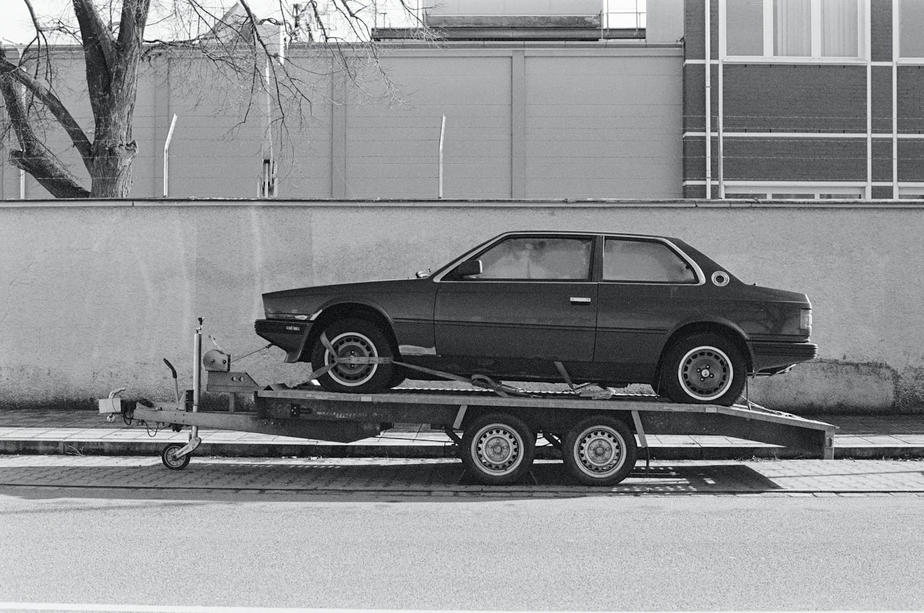 Open car trailer carrying a coupe
