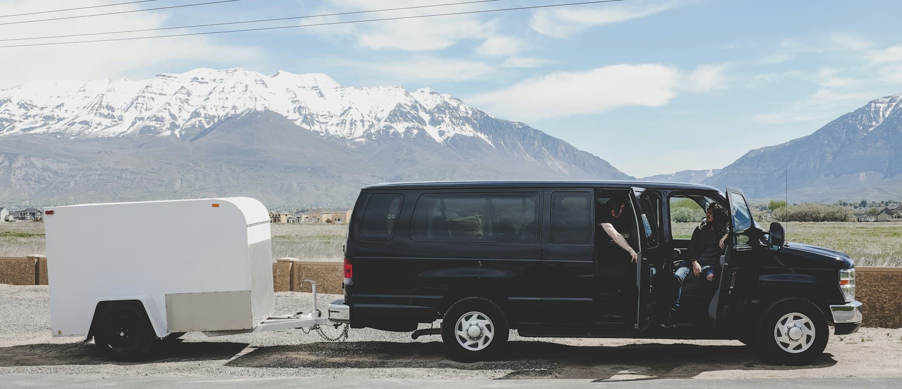 White enclosed cargo trailer hitched to a black van
