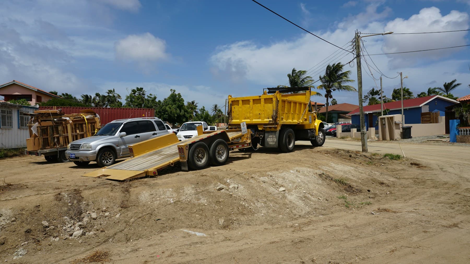 Yellow tilt-deck equipment trailer with ramp lowered