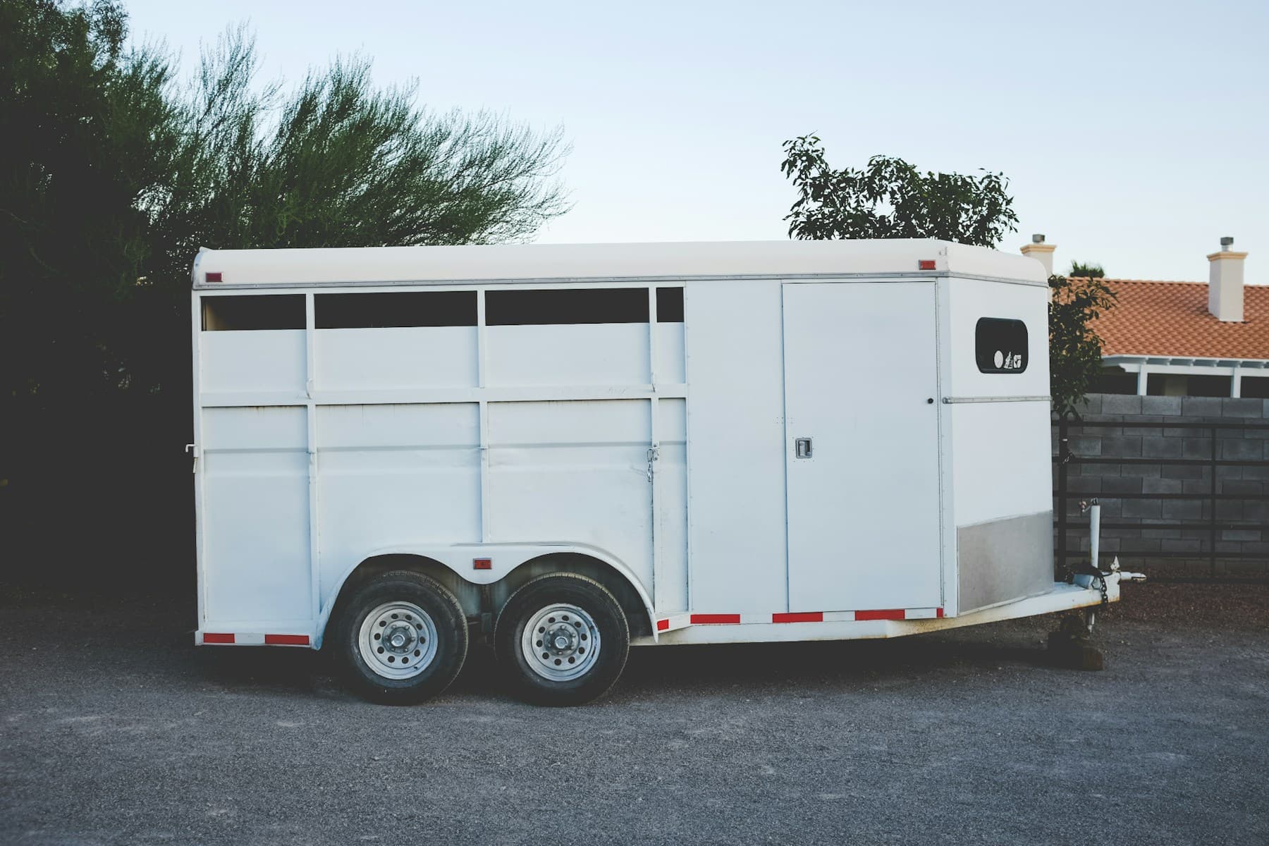 White two-horse stock trailer on a gravel lot