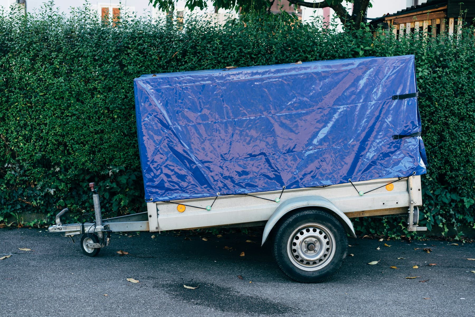 Single-axle utility trailer with a blue tarp cover
